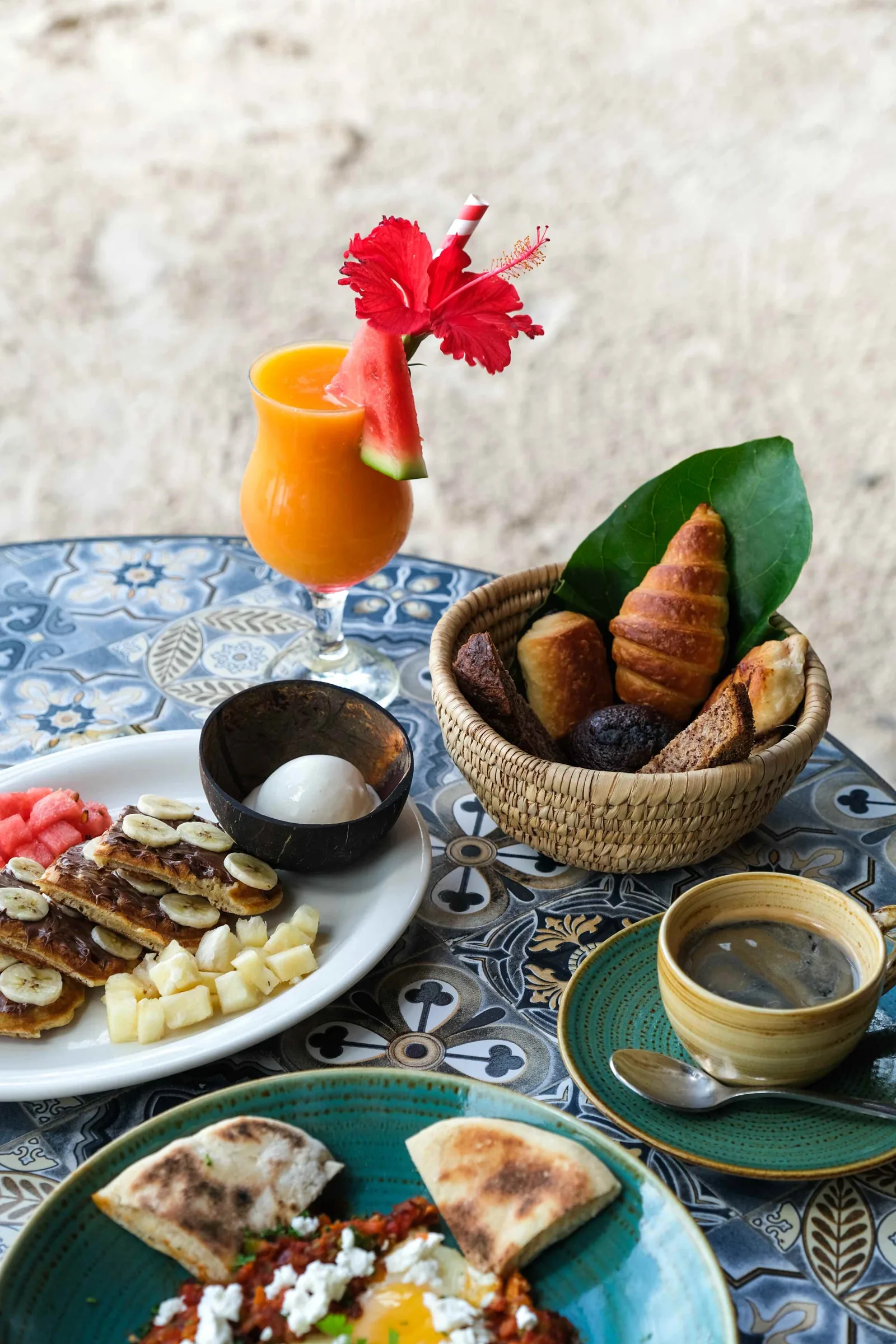 Desayuno con fruta, pan y zumo entre palmeras