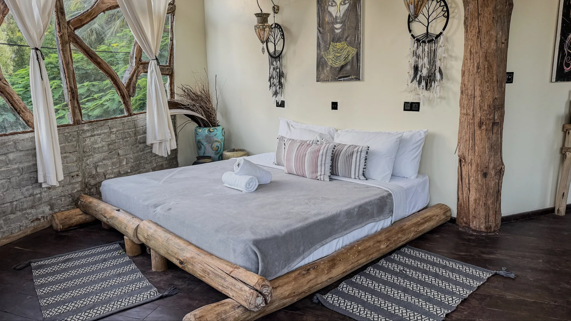 Dormitorio de tree house del Nest con arte africano, dreamcatcher y la luz del ventanal en arco